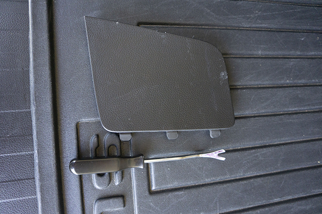 Photo of 2010 Subaru Outback tail light access cover in hatchback lid and the trim tool used to remove it.